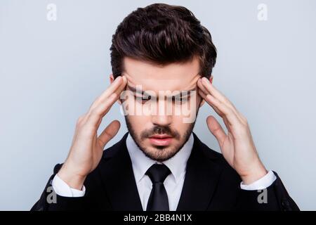 Nahaufnahme des traurigen Mannes im schwarzen Anzug, der seine Tempel berührt, weil er an Migräne erkrankt ist Stockfoto