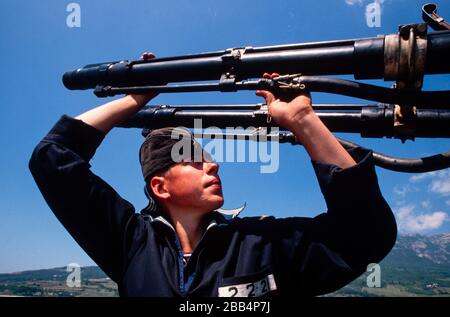 Ein junger KGB-Marine-Rating reinigt das Revolvergewehr auf einem Grenzschiff Schwarzes Meer, Krim, UdSSR, August 1990 Stockfoto