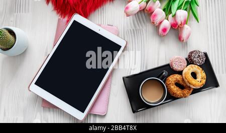 Tablette auf einem schön dekorierten weißen Holztisch. Designfotografie im Stil. Texturen und Mockup-Konzept Stockfoto