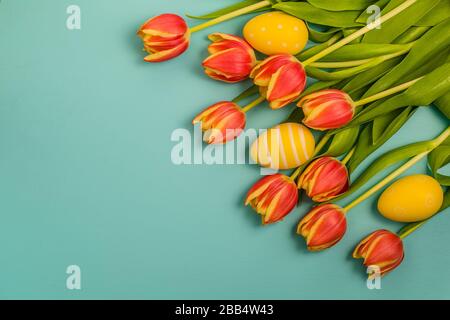 Ein Haufen frischer rosafarbener und weißer Tulpenblumen mit grünen Blättern und Ostereiern, die auf Holztisch gelegt werden, Kopierraum, Draufsicht, flaches Design im Frühling. Stockfoto