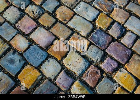 Typische bunte Kopfsteinpflaster, Bürgersteig aus roten, gelben, orangefarbenen, grauen, blauen, violetten und weißen, rechteckigen Steinstücken, Draufsicht. Stockfoto