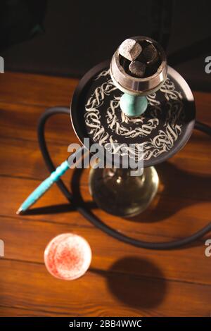 Rauch aus einer Kapuze in einer Bar auf einem Tisch auf dunklem Hintergrund. Rauchen für Entspannung. Stockfoto