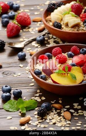 Obst gesund Müsli mit Pfirsich Erdbeere Mandeln und Black in Ton Teller auf hölzernen Küchentisch Stockfoto