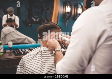 Barber schneidet den Kunden im Salon sorgfältig ab Stockfoto