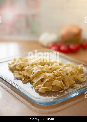 Hausgemachte frische Tagliatelle Pasta in der Küche auf Glastablett auf Küchenarbeitsoberfläche Stockfoto