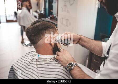 Friseur rasiert Kunden in Barbershop. Barbershop Konzept Stockfoto