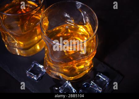 Zwei Gläser Whisky mit Eis auf einem schwarzen Tisch Stockfoto