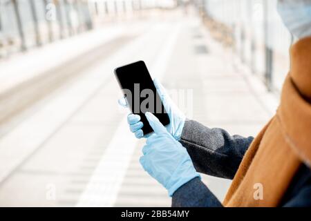 Frau in medizinischen Handschuhen, die ein Smartphone im Freien hält, Telefon mit schwarzem Bildschirm zum Kopieren von Paste. Konzept der Online-Kommunikation und der sozialen Distanz während einer Epidemie Stockfoto