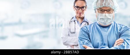 Männer im mittleren Alter Chirurg in Brille mit blauem Kleid, Gesichtsschutzmaske und Hut; junge weibliche Ärztin in weißem Kleid mit Brille und Stethoskop Stan Stockfoto