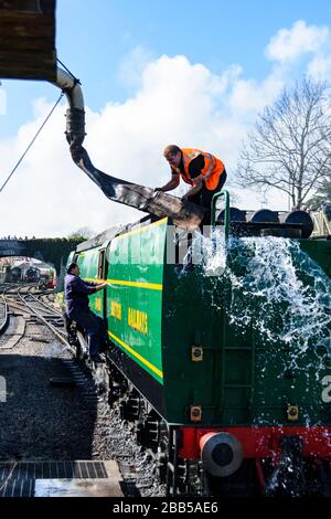 Wasser aus der Ausschreibung des Battle of Britain Class Steam Loco 34081 verschüttet, nachdem der Feuerwehrmann den Tender mit Wasser gefüllt hat. Stockfoto