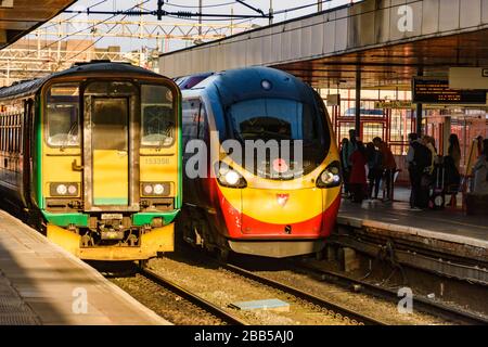 Virgin Trains Pendolino kommt am Bahnhof Coventry neben einem lokalen Service der London Midlands Class 153 an. Stockfoto