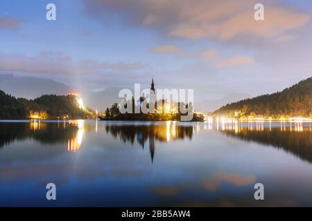 Abend herbst Blick auf See von Bled in den Julischen Alpen, Slowenien. Wallfahrtskirche der Himmelfahrt der Maria im Vordergrund. Landschaftsfotografie Stockfoto