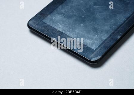Schwarz verkratztes Tablett mit einer Schutzfolie auf grauem Hintergrund. Schützen Sie den Bildschirm Ihres Geräts Stockfoto