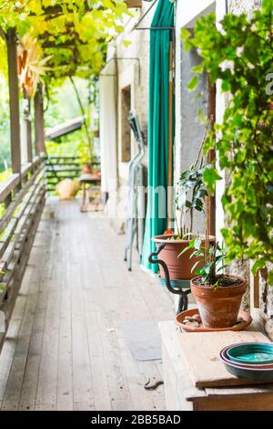 Ein Balkon in einem historischen Bauernhaus in Trient, Italien. Der Balkon öffnet das obere Stockwerk. Hier sind Blumenkannen und viele Gegenstände. Stockfoto