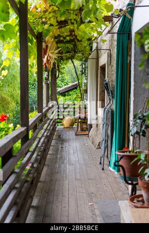 Ein Balkon in einem historischen Bauernhaus in Trient, Italien. Der Balkon öffnet das obere Stockwerk. Hier sind Blumenkannen und viele Gegenstände. Stockfoto