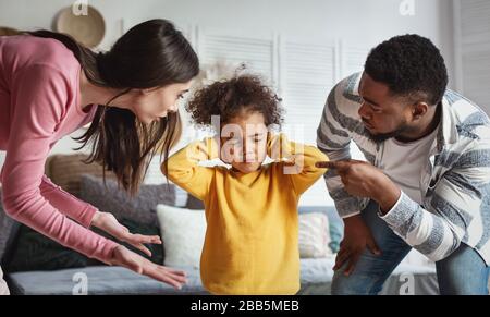 Eltern erschrecken das Kind. Mädchen schloss ihre Ohren und Augen Stockfoto