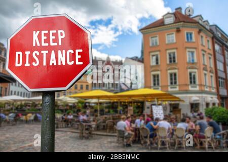 Konzept der sozialen Distanzierung. Schild mit "Abstand halten"-Wort mit Café mit unscharfem Hintergrund. Vorbeugende Maßnahmen zur Eindämmung des Corona-Virus Stockfoto