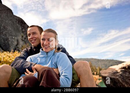 Glückliches Paar mittlerer Erwachsener sitzt gern zusammen auf der Bergkuppe. Stockfoto