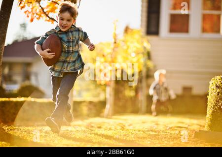 Laufen Junge spielt Fußball im Hinterhof mit seinem Bruder. Stockfoto