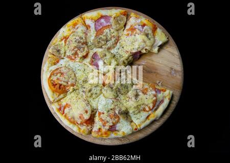 Pizza mit Salami, Mozzarella, Tomaten, Bananen steht auf einem Holzbrett. Stockfoto