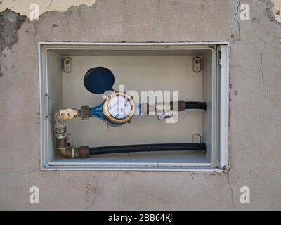 Ein Hauswasserzähler und Absperrventil in einer Außenwand vor einem Haus in Funchal, Madeira. Stockfoto