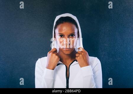 Junge Frau in Sportkleidung mit Blick auf die Kamera. Selbstbewusste und süßte Sportlerin im Studio. Stockfoto