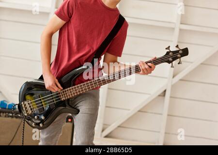 Teenager, der eine Bassgitarre in einer Garage spielt, Stockfoto