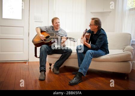 Mittlerer Erwachsener und reifer Mann, der akustische Gitarren spielt. Stockfoto