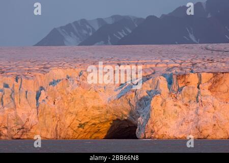 Eingang der Eishöhle bei Sonnenuntergang im Kongsbreen-Gletscher, der in Kongsfjorden, Svalbard/Spitzbergen, Norwegen kalbt Stockfoto