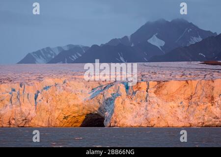 Eingang der Eishöhle bei Sonnenuntergang im Kongsbreen-Gletscher, der in Kongsfjorden, Svalbard/Spitzbergen, Norwegen kalbt Stockfoto