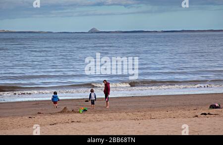 Portobello, Edinburgh, Schottland, Großbritannien. März 2020. Wetter, bewölkt am Nachmittag am sehr ruhigen Strand mit gelegentlichem Regenschauer. Mutter und zwei Leiern am Ufer bauen Sandburgen. Stockfoto