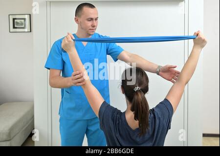 Ein junger männlicher Physiotherapeut hilft einem Teenager-Mädchen bei Dehnübungen Stockfoto