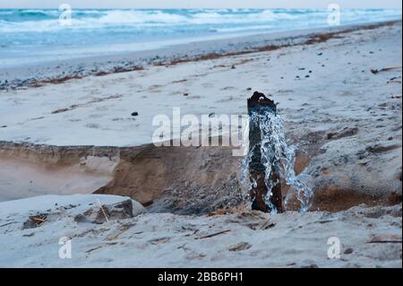 Wasser aus Kanalrohr, Abwasser, der am Ufer des Meeres Stockfoto