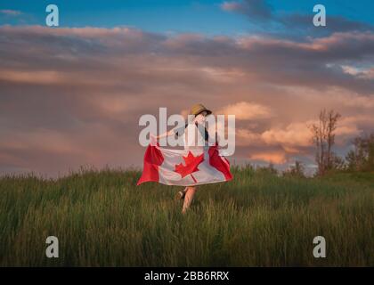 Junge, der durch ein Feld läuft, das eine kanadische Flagge hält, Bedford, Halifax, Nova Scotia, Kanada Stockfoto