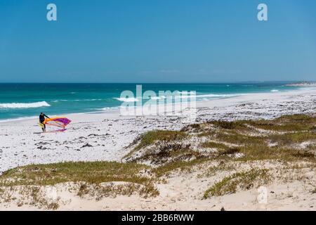 Windsurfer führt die Rigg entlang des berühmten windigen Kitesurfstrands am Haakgat Point, Otto Due Plessis Drive, Melkbosstrand, Capte Town, Südafrika Stockfoto