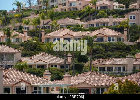 Reihe nach einer Reihe von einstöckigen, rosafarbenen Häusern, die auf einem Hügel in einer Ruhestandsgemeinde im Süden Kaliforniens errichtet wurden. Palmen dot the Real Estate. Stockfoto