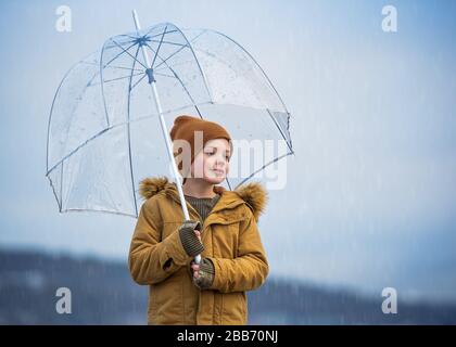 Smiling Boy stand unter einem Regenschirm in The Rain, Bedford, Halifax, Nova Scotia, Kanada Stockfoto