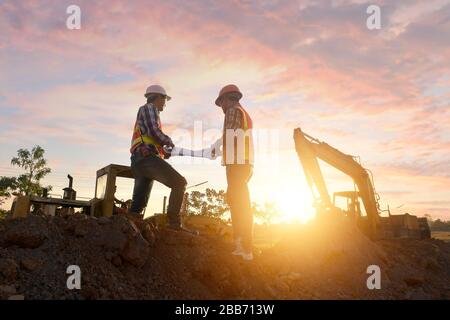 Zwei Bauarbeiter auf einer Baustelle, die sich die Pläne betrachtet, Thailand Stockfoto