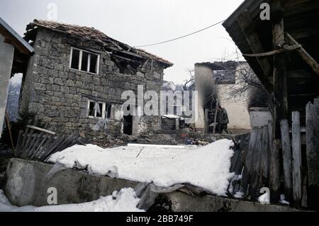 Januar 1994 während des Krieges in Zentralbosnien: Noch immer zerschlägende Häuser, während Soldaten der Rama Brigade der HVO durch das bosnisch-muslimische Dorf hier spazieren, das zwei Tage zuvor gefangen genommen wurde. Stockfoto