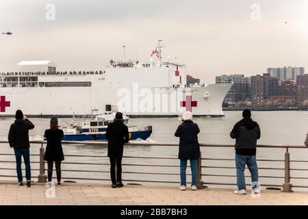 Besucher des Hudson River Park in New York begrüßen das USNS Comfort Hospitalschiff, das am Montag, den 30. März 2020 in New York ankommt. Das Schiff wird am Pier 90 berten und seine 1.000 Krankenhausbetten nutzen, um nicht-COVID-19-Patienten zu dienen, die einen Teil der Belastung der New Yorker Krankenhäuser übernommen haben. (© Richard B. Levine) Stockfoto