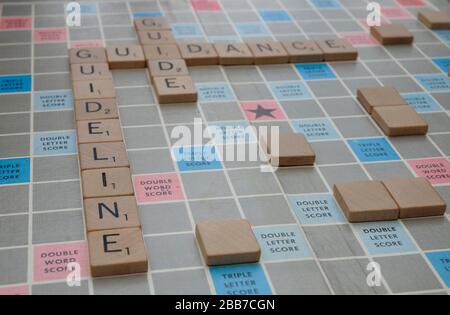 Anleitung, Leitfaden und Leitfaden Worte auf einem Scrabble Board mit dem Coronavirus Covid-19 Pandemie verbunden geschrieben Stockfoto