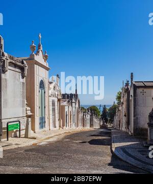 Reihe von Mausoleen in Cemitéro do Alto de São João mit Fluss Tejo im Hintergrund. Stockfoto