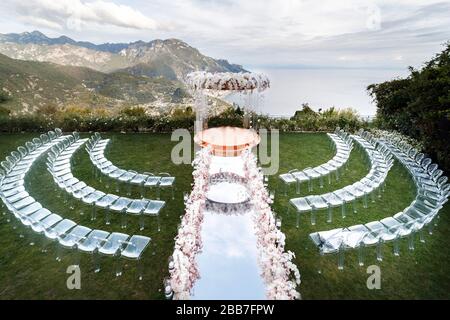 Ein wunderbarer Ort in den Dekorationen und Blumen für die Hochzeitsfeier. Mit transparenten Stühlen am Meer. Stockfoto