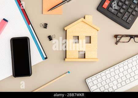 Arbeiten Sie zu Hause. Schreibtisch mit Haus-Symbol, Smartphone, Tastatur und Bürozubehör Stockfoto