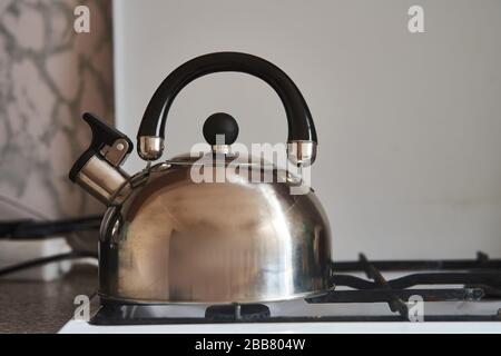 Eiserner grauer Wasserkocher steht auf einem Gasherd Stockfoto
