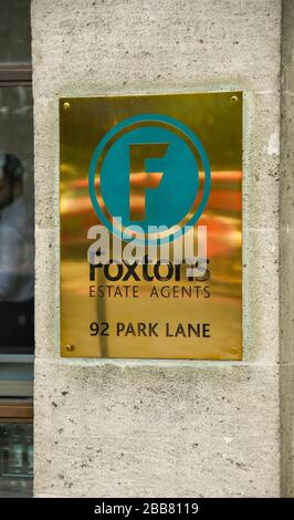 LONDON, ENGLAND - JUNI 2018: Messingschild an der Wand vor den Büros der Foxtons Immobilienmakler an der Park Lane im Zentrum Londons Stockfoto