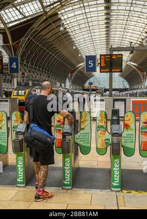 LONDON, ENGLAND - JULI 2018: Bahnreisende, die eine automatische Fahrkartensperre auf dem Konkurs am Bahnhof London Paddington passieren Stockfoto