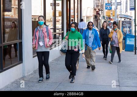 Menschen, die Gesichtsmasken tragen, während sie während der Covid-19-Epidemie (Coronavirus) auf den Bürgersteigen von New York City spazieren. Stockfoto