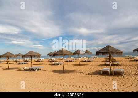 Leerer Strand mit Sonnenschirmen und liegen, Albufeira, Algarve, Portugal Stockfoto