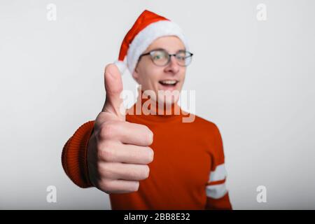 Glücklicher gutaussehender Mann in weihnachtshut mit Daumen nach oben. Stockfoto